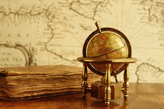 Globe And Vintage Book Against Map On A Wall.