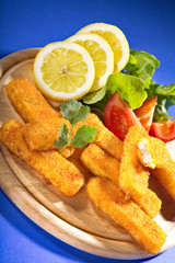 Fischstäbchen mit Salat und Zitrone angerichtet Nahaufnahme