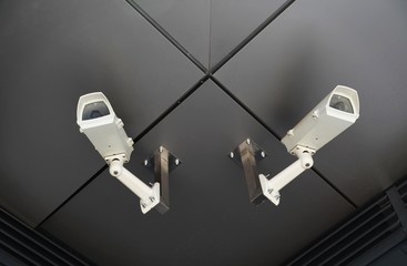 two surveillance cameras mounted on outdoor ceiling