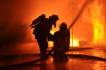 Obraz premium Straż pożarna przed ścianą płomienia