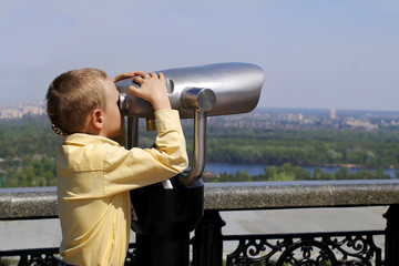 Fototapeta na wymiar Boy with telescope on panorama terrace