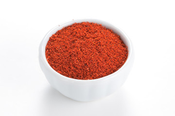 Paprika ground in a white bowl on white background.