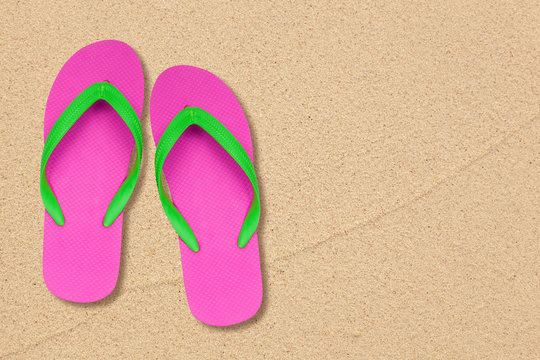 pink and green flip flops on the beach with space
