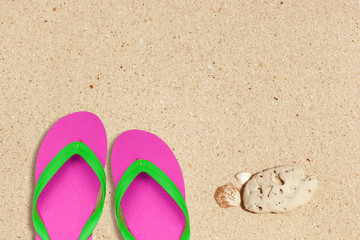 pink and green flip flops on the beach with space
