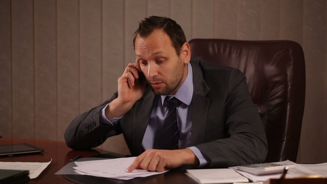 Angry boss talking on the phone in office