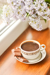 Obraz na płótnie Canvas Ceramic cup with coffee and bouquet of lilac
