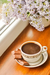 Ceramic cup with coffee and bouquet of lilac
