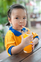 Little girl drinking orange juice
