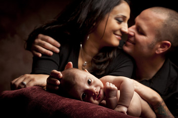 Mixed Race Couple Lovingly Look On While Baby Lays on Pillow