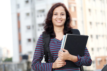 Cheerful female student holding text books