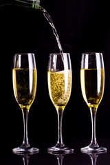 Two full glasses of champagne and one being filled