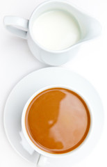White cup of coffee next to a milk pot