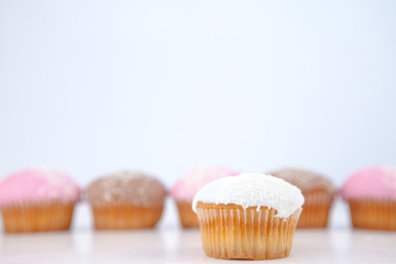 Muffin placed in front of a line of muffin with icing sugar