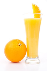 Orange placed next to a glass of orange juice