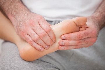 Podiatrist massaging the foot of a woman while holding it on his