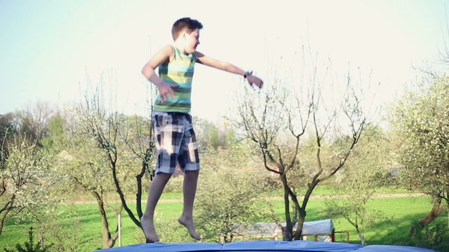 Happy young boy jumping on trampoline, slow motion