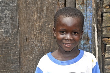 Afrikanischer Junge vor seinem Zuhause