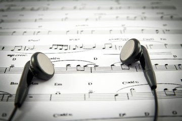 An ear phone on the top of a music sheet
