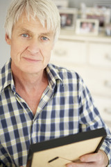 Senior man with photographs at home