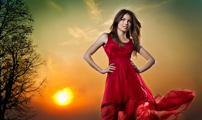 lady in red and colorful sky behind
