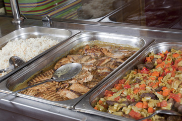 Hot trays with cooked food close-up in dining room