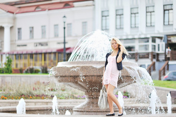 Beautiful young woman posing by the fountain in the old town