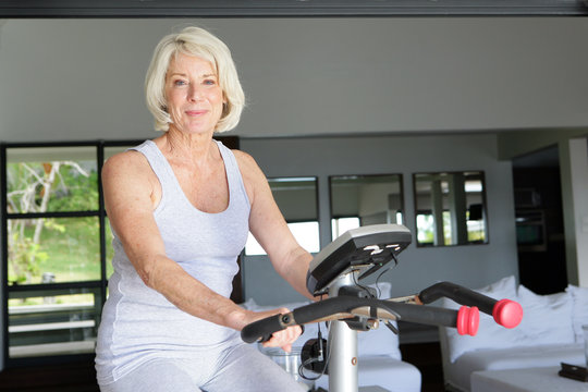Mature Woman Using An Exercise Bike At Home