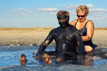 happy mature couple taking mud treatment on summer day