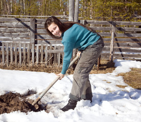 A young girl digs the garden in early spring