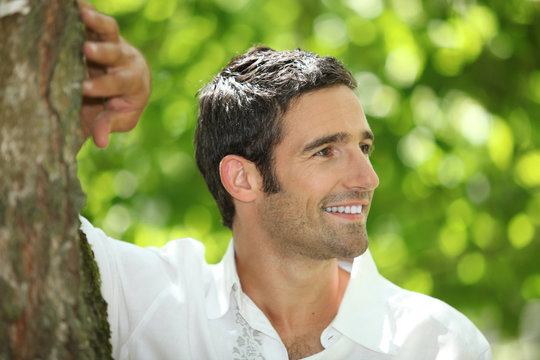 Handsome Man Leaning Against A Tree