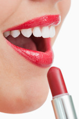 Naklejka premium Woman opening her mouth while applying lipstick on her lips
