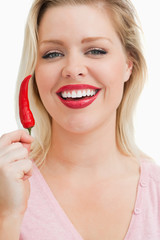 Cheerful blonde woman showing a chili