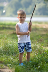 boy with a stick in hands, on the bank of the lake