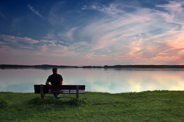 Fototapeta na wymiar Mężczyzna na ławce nad jeziorem