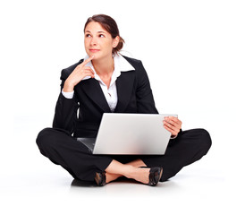 Young business woman sitting on the floor with laptop, thinking