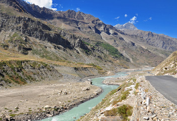 wide shot of valley with road along mountain stream