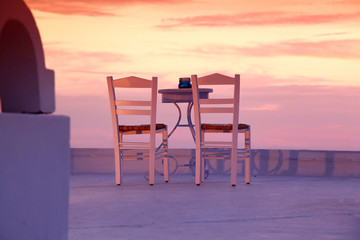 Santorini restaurant with chairs against sunset, Greece