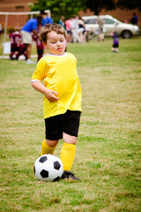 Obraz premium Young boy playing soccer during organized league game