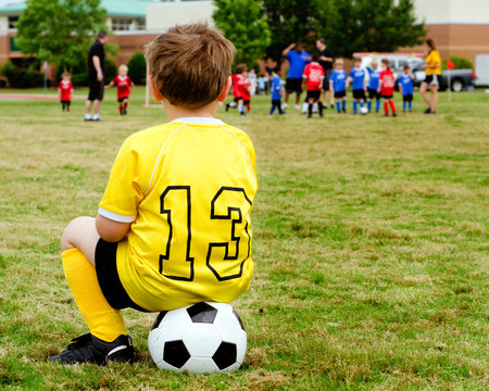 Boy  watching organized youth soccer game from sidelines