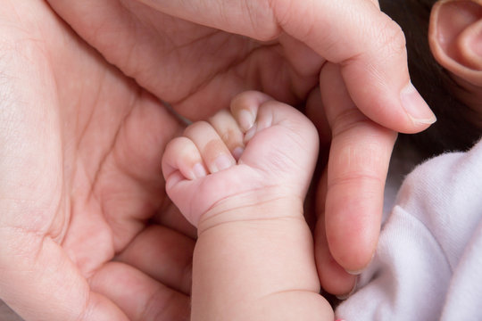 Female hand holding newborn baby hand