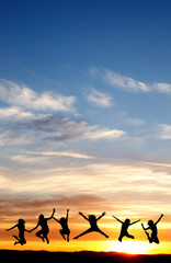 silhouette of teenagers jumping in sunset for fun