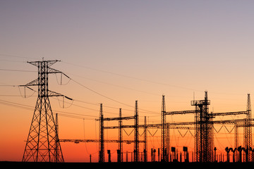 Silhouetted power pylons against a red sky at sunset