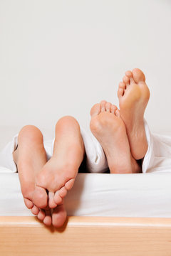 F&uuml;&szlig;e eines Paares im Bett.