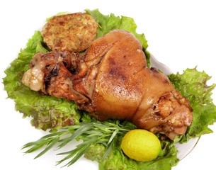 roasted pork shank with green leaves, lemon
