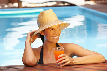 Frau mit Strohhut am Pool