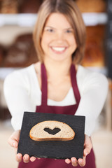verkäuferin zeigt eine brotscheibe mit herz