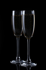 two glasses of champagne on black background