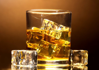 glass of whiskey and ice on brown background