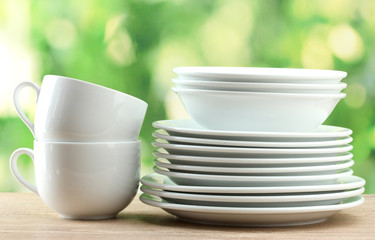 Clean dishes on wooden table on green background
