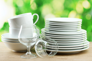 Clean dishes on wooden table on green background